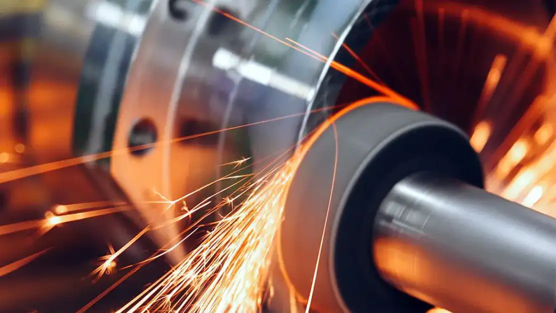 Una pieza metálica rotada, que saca chispas, como parte de un proceso de metalurgia.